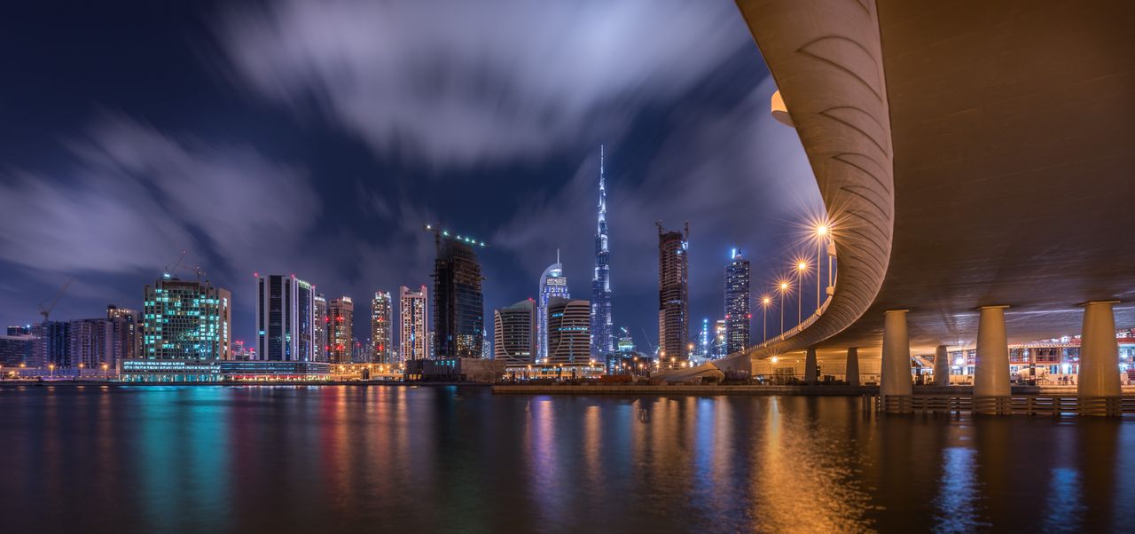 Stunning night view of Dubai skyline featuring the illuminated Burj Khalifa and reflections on water.