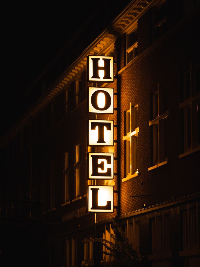 A bright hotel sign glowing on a building facade during nighttime.