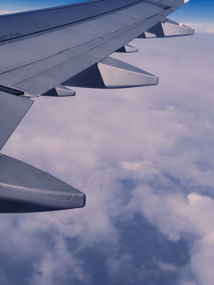 Airplane wing soaring above clouds, capturing serene view during daylight flight.